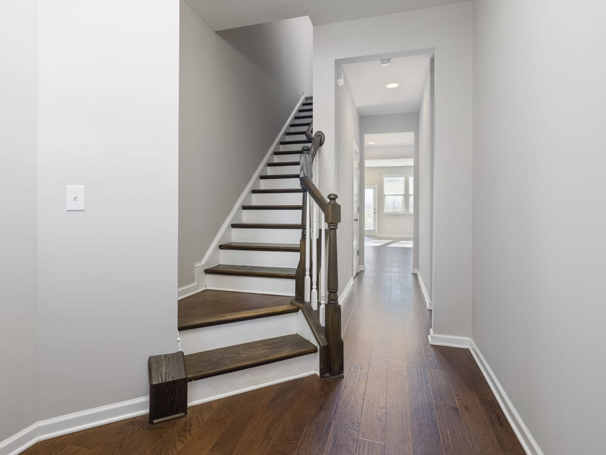 A turning staircase beside a narrow hallway and doorway.